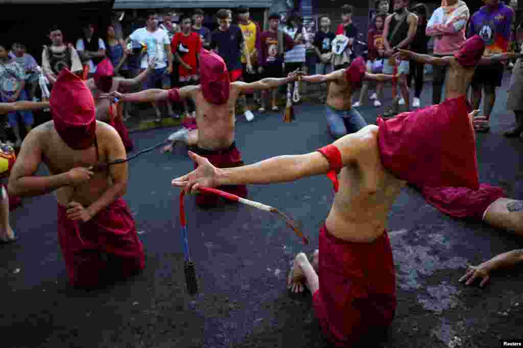 People watch as Filipino penitents perform self-flagellation on Maundy Thursday in Mandaluyong City, Metro Manila, Philippines.