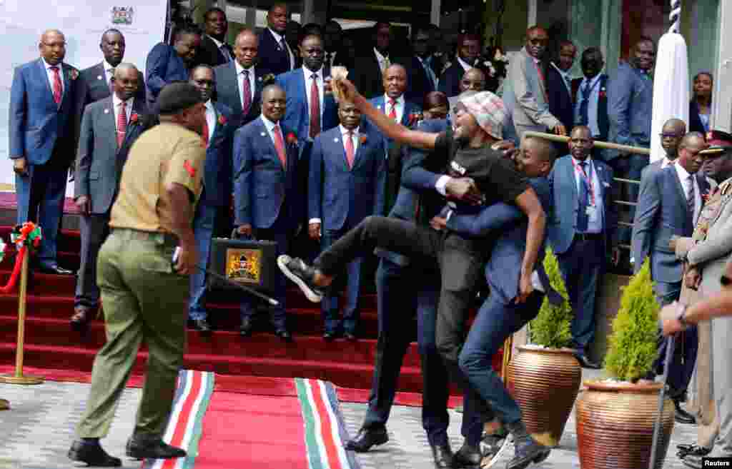 Police officers detain Julius Kamau, a vocal Kenyan rights activist, as he protests outside the National Treasury buildings in Nairobi.