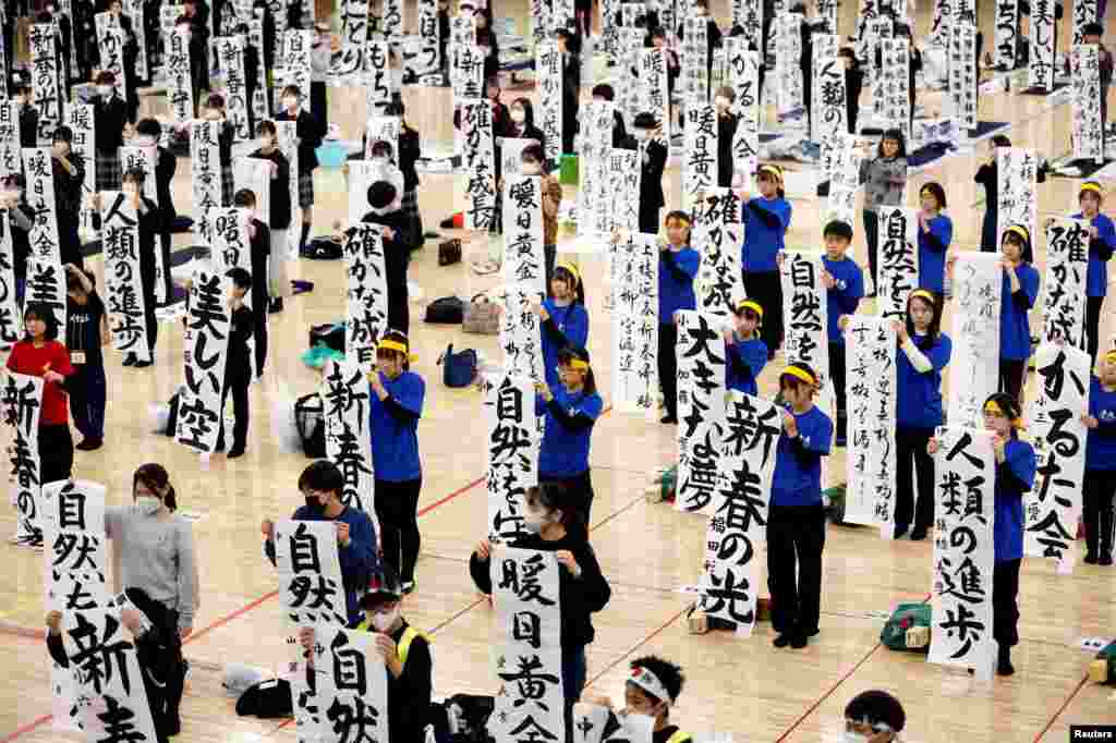 Participants show off their writings in a New Year calligraphy contest at Nippon Budokan in Tokyo.