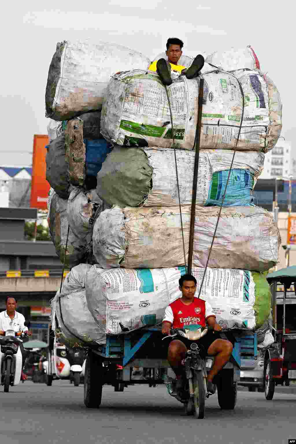 A man drives a motor-cart carrying scrap for recycling, along a street in Phnom Penh, Cambodia.