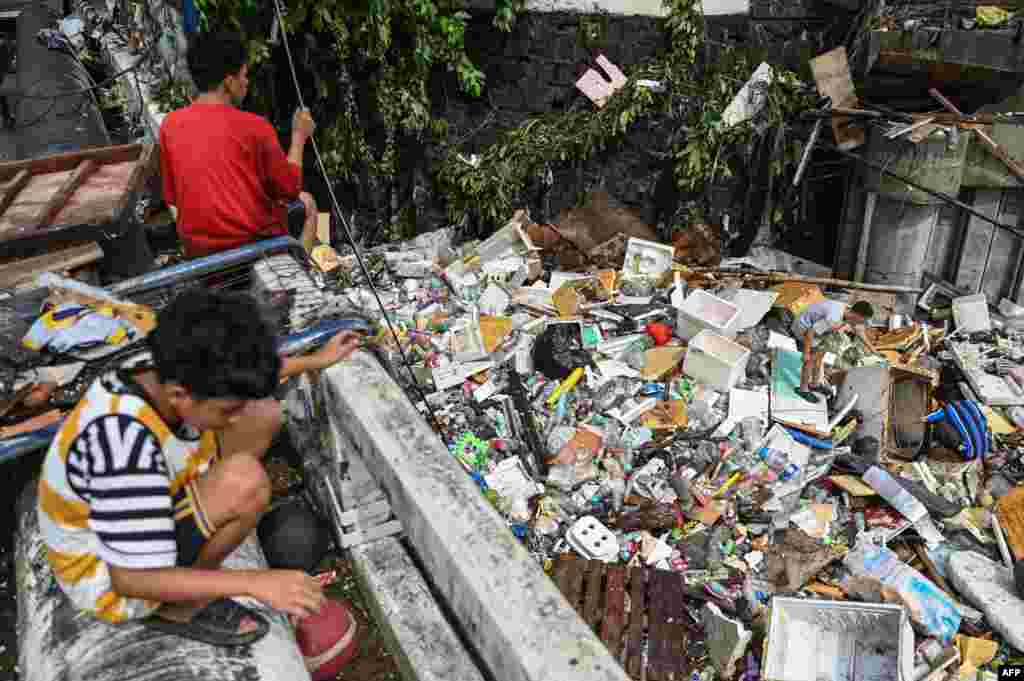 Residents pick up debris in a river in the aftermath of Typhoon Gaemi in Manila, Philippines, July 25, 2024.