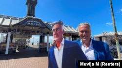 Steve Endacott, an independent candidate in the Brighton Pavilion race, poses with his AI avatar outside Brighton pier in southern Britain, June 17, 2024. REUTERS/Muvija M