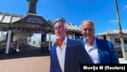 Steve Endacott, seorang kandidat independen dalam pemilihan Brighton Pavilion, berpose dengan avatar AI-nya di luar dermaga Brighton di Inggris selatan, 17 Juni 2024.