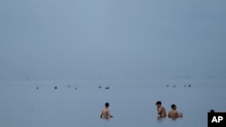 FILE - People swim in the ocean off of Crandon Park, July 28, 2023, in Key Biscayne, Fla (AP Photo/Rebecca Blackwell, File)
