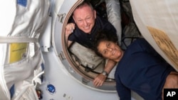 In this photo provided by NASA, Boeing Crew Flight Test astronauts Butch Wilmore, left, and Suni Williams pose for a portrait inside the vestibule between the forward port on the ISS's Harmony module and Boeing's Starliner spacecraft on June 13, 2024.