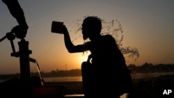 A youth cools off under a hand pump at the sunset during hot weather in Lahore, Pakistan, May 28, 2024. 