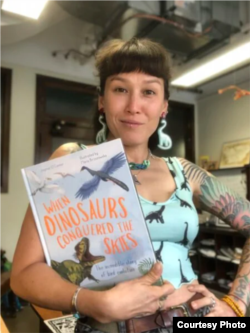 Jingmai O’Connor holds WHEN DINOSAURS CONQUERED THE SKIES, illustrated by Maria Brzozowska. (Image courtesy of publisher The Quarto Group.)