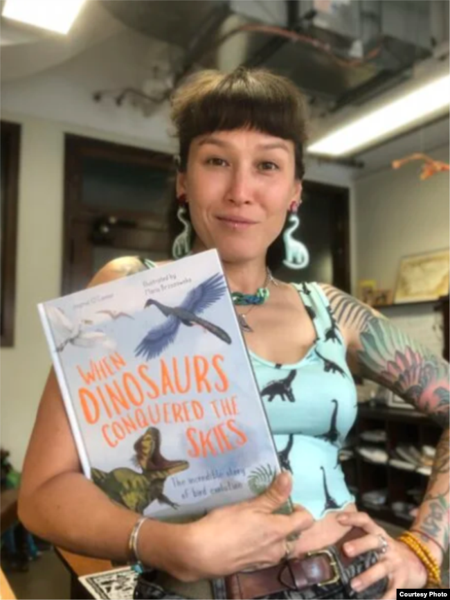 Jingmai O’Connor holds WHEN DINOSAURS CONQUERED THE SKIES, illustrated by Maria Brzozowska. (Image courtesy of publisher The Quarto Group.)