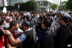 Riot police stand guard as thousands of protesters gather outside the French embassy in Tunis, Tunisia, Oct. 18, 2023, in solidarity with Palestinians in Gaza.