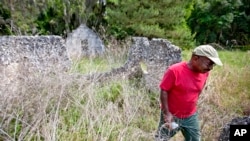 FILE - Ire Gene Grovner walks through remnants of the old slave's quarters, May 16, 2013, at the Chocolate Plantation where his ancestors lived some eight generations ago on Sapelo Island, Ga.