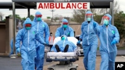 FILE - A person is taken on a stretcher into Houston's United Memorial Medical Center after going through testing for COVID-19, March 19, 2020, in the early days of the pandemic in the U.S.