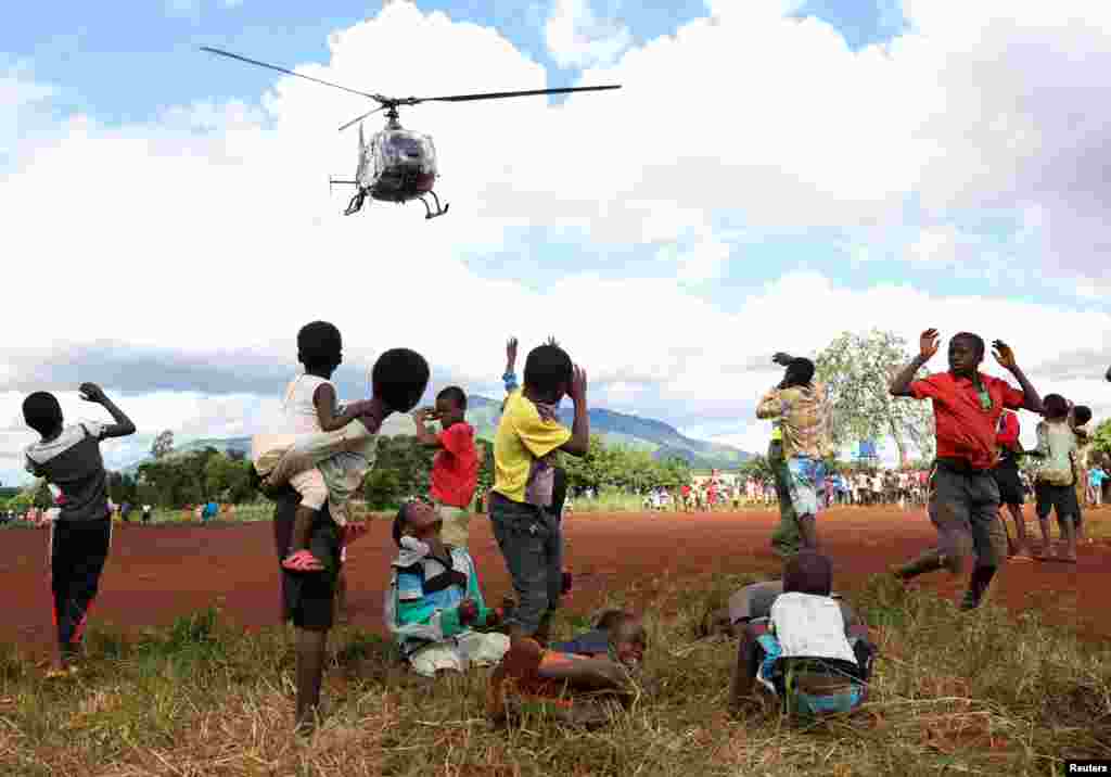 Children in Mulanje looks on as a military helicopter carry doctors and medical supplies to Muloza on the border with Mozambique which are cut off after the tropical Cyclone Freddy outside Blantyre, Malawi, March 18, 2023.