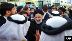 A handout picture provided by the Iranian presidency on May 4, 2023, shows Iranian President Ebrahim Raisi, center, surrounded by people during his visit to the holy shrine of Sayyida Zaynab in the southern suburbs of Damascus, Syria.