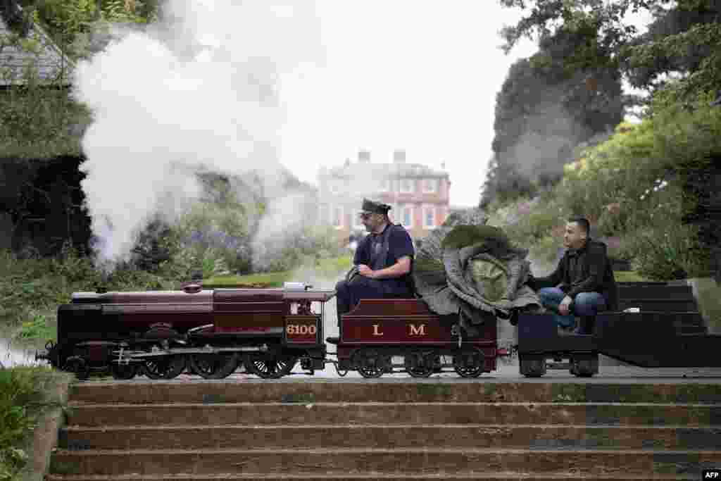 Steam engine driver Bob Corrie, left, and grower Paul Proud transport Proud&#39;s cabbage that won its category in the giant vegetable competition at the Harrogate Autumn Flower Show held at Newby Hall country house, near Ripon, northern England. (Photo by Oli SCARFF / AFP)