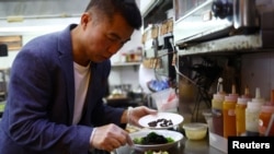 Pemilik restoran Francis Ng menambahkan serangga hitam ke dalam semangkok salad di restoran miliknya House of Seafood di Singapura, pada 16 Juli 2024. (Foto: Reuters/Edgar Su)