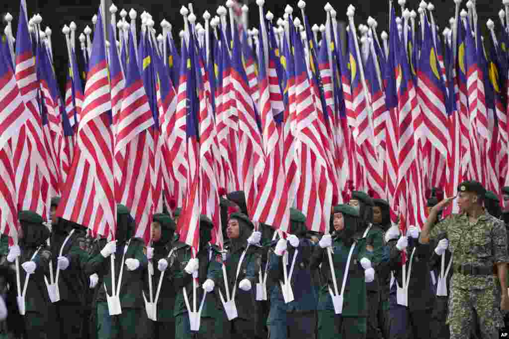 Members of Malaysian school-based government youth organization KRS hold their national flags during the National Day parade in Putrajaya.