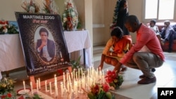 FILE - Mourners place candles at Radio Amplitude FM where a portrait of slain journalist Arsene Salomon Mbani Zogo, also known as "Martinez," has been placed as a tribute to him, in the Elig Essono district in Yaounde, Cameroon, Jan. 23, 2023. 