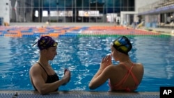 Las hermanas ucranianas Maryna, a la izquierda, y Vladyslava Aleksiiva hablan durante una sesión de práctica en Kiev, Ucrania, el martes 21 de febrero de 2023.