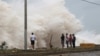 People stand in front of waves crashing against the shore as Hurricane Beryl moves south of the island, in Santo Domingo, Dominican Republic, July 2, 2024. 