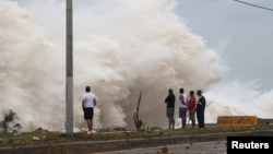 Orang-orang berdiri di pantai menghadap terjangan ombak, saat Badai Beryl bergerak ke selatan pulau, di Santo Domingo, Republik Dominika, 2 Juli 2024. (REUTERS/Erika Santelices)