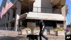 FILE - A Federal Bureau of Investigation police officer walks with his working dog outside Federal Bureau of Investigation building headquarters in Washington, Aug. 13, 2022.