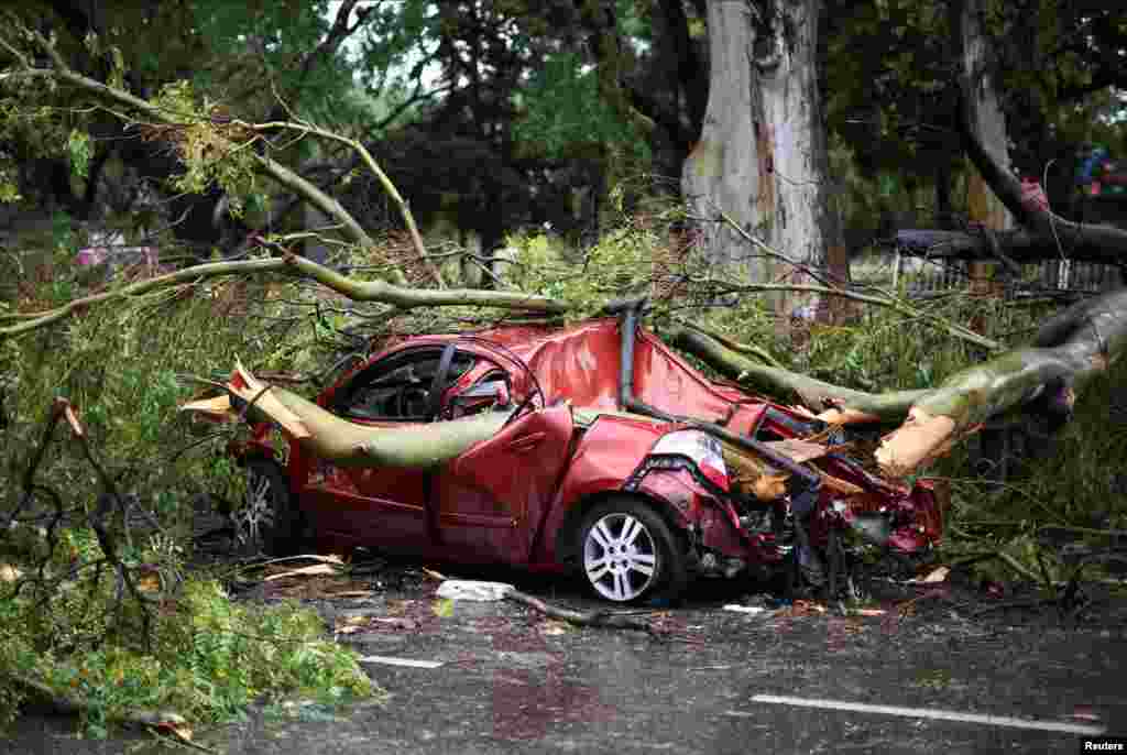 Tree branches lie on top of a damaged car after a severe storm, in Buenos Aires, Argentina.