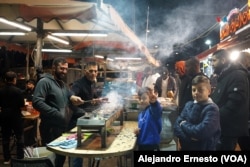 Un grupo de palestinos compra brochetas cerca de la Ciudad Vieja de Jerusalén, después de realizar un ayuno diurno, obligatorio para los musulmanes durante el mes sagrado del Ramadán.