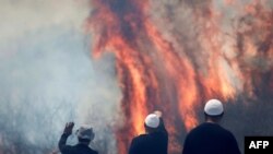 Local Druze men watch the flames burning a field after rockets launched from southern Lebanon landed on the Banias area in the Israel-annexed Golan Heights&nbsp;amid ongoing cross-border clashes between Israeli troops and Hezbollah fighters.