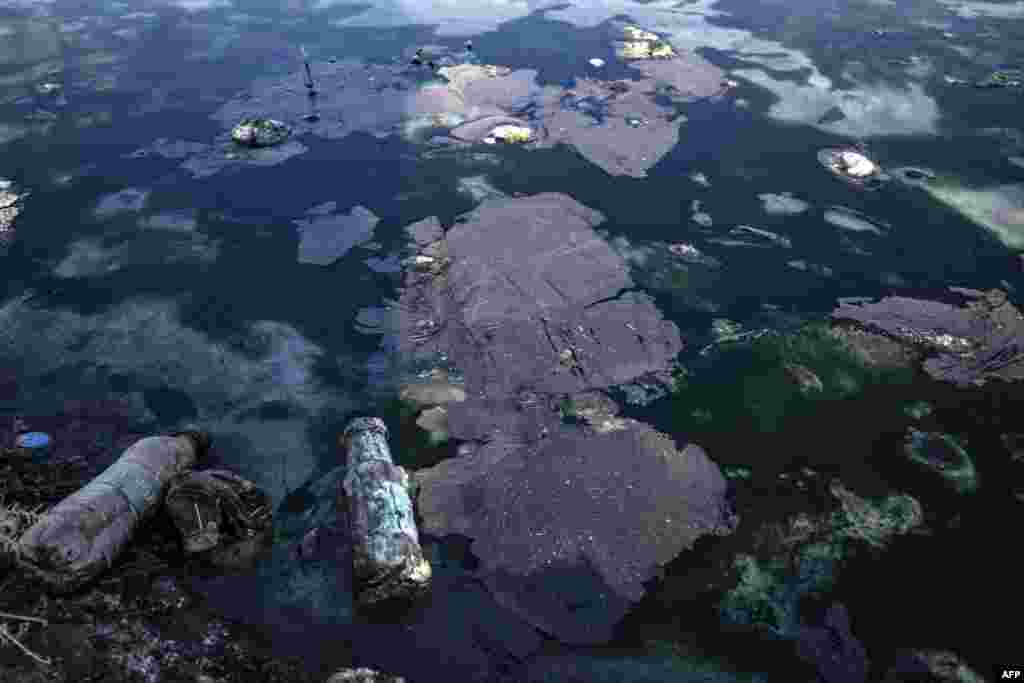 Oil and plastic bottles litter a river polluted by a nearby oil field in the countryside of Rmeilan, in Syria&#39;s northeastern Hasakeh province.