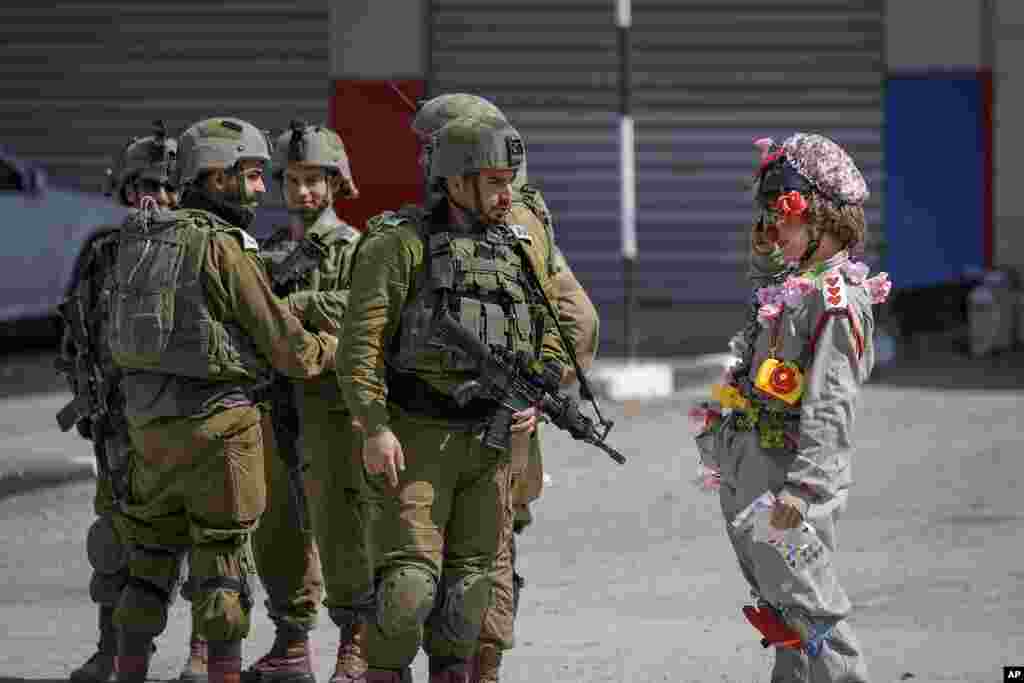 An Israeli activist dressed as a clown salutes a group of Israeli soldiers during a solidarity rally by Israeli left-wing activists in the West Bank town of Hawara.