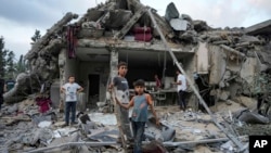 FILE — Palestinians look at the destruction after an Israeli airstrike in Deir al Balah, Gaza Strip, April 30, 2024.