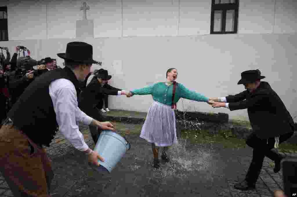 Hungarian men wearing folk costumes pour water onto women during a traditional a Easter Monday celebration in Holloko, Hungary, April 10, 2023.