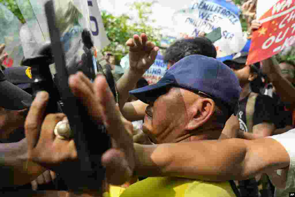 Activists try to hold their ground as police tried to block them from holding a protest near the Chinese consulate in Makati, Philippines. The group is protesting the continued aggression of China at the disputed South China Sea. (AP Photo/Aaron Favila)