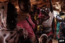 FILE - Mothers wait at a malnutrition center to register for food aid for their children in the Tiamushro camp for internally displaced persons (IDP) in Kadugli, South Kordofan state, Sudan, June 17, 2024.