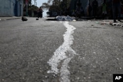 Blood streams from a body lying in the street in the Petion-ville area of Port-au-Prince, Haiti, March 20, 2024.