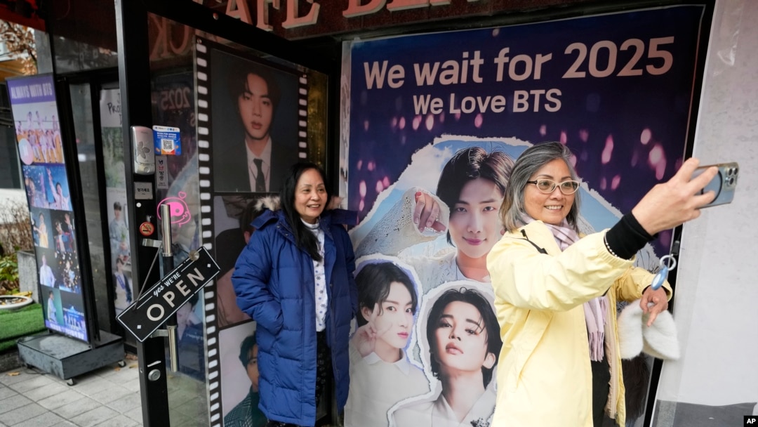 Seorang perempuan berswafoto di depan foto anggota grup K-Pop BTS di sebuah kafe di Seoul, Korea Selatan, 11 Desember 2023. (Foto:Ahn Young-joon/AP Photo)