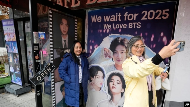 Seorang perempuan berswafoto di depan foto anggota grup K-Pop BTS di sebuah kafe di Seoul, Korea Selatan, 11 Desember 2023. (Foto:Ahn Young-joon/AP Photo)