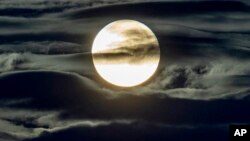 In this Sept. 2, 2020 file photo, the full moon shines surrounded by clouds in the outskirts of Frankfurt, Germany. (AP Photo/Michael Probst, File)