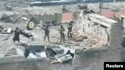 FILE - A still image from video released by Russia's Wagner Group press service, shows what it said to be Wagner fighters standing on top of a building in Bakhmut, Ukraine, in this still image taken from video released March 2, 2023.