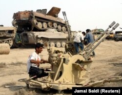 Körfez Savaşı'ndan sonra Irak tanklarının enkazından hurda ayıklamaya çalışan bir Iraklı (2003)