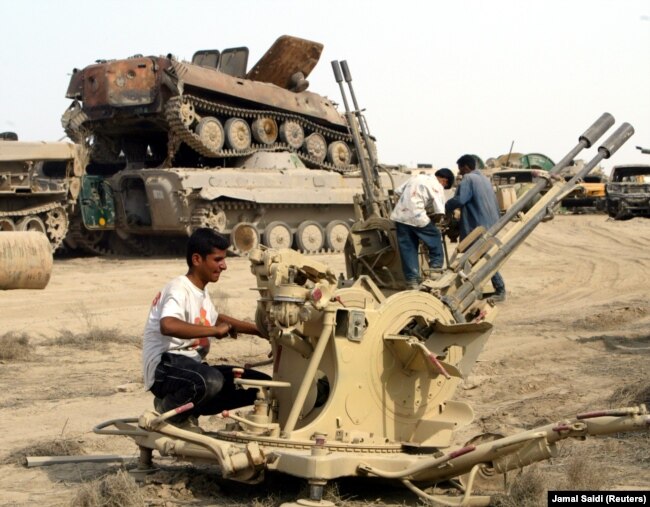 Körfez Savaşı'ndan sonra Irak tanklarının enkazından hurda ayıklamaya çalışan bir Iraklı (2003)