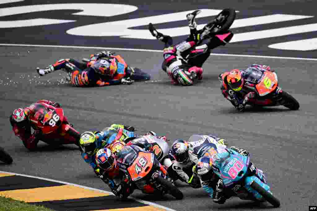 Spain&#39;s Red Bull KTM Ajo rider Jose Antonio Rueda (L) and Italy&#39;s MTA Team rider Stefano Nepa crash as Colombia&#39;s CFMOTO Aspar Team rider #80 David Alonso leads the pack during the Italian Moto 3 race at Mugello.