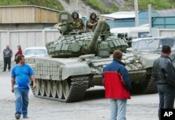 Penduduk setempat melihat kendaraan lapis baja Rusia menuju Provinsi Ossetia Selatan yang memisahkan diri di Georgia, di Ossetia Utara, Rusia, Jumat, 8 Agustus 2008. (Foto: AP)