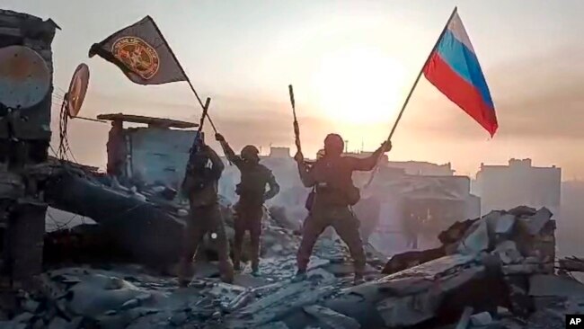 Mercenarët e grupit Wagner duke valëvitur flamurin rus mbi një godinë të shkatërruar në Bakhmut, Ukrainë (20 maj 2023)