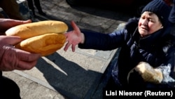 (FILE) A resident receives bread from a food distribution in Ukraine.