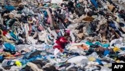 Una mujer busca ropa entre las prendas desechadas en Alto Hospicio, en el desierto de Atacama, Chile, el 26 de septiembre de 2021.