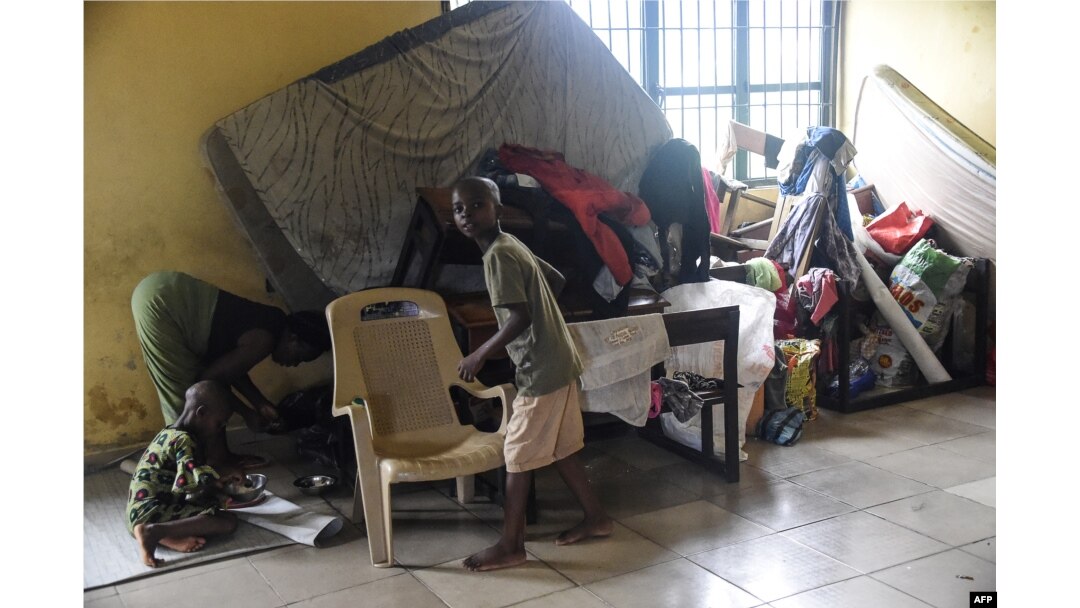 FILE - A mother and children stand beside wares and mattresses in an internally displaced people's camp, where flood evacuees are accommodated, at Community Primary School in Ihuike, Niger delta region of Ahoada, Rivers State, southern Nigeria, on Oct. 21, 2022.