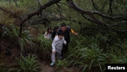 一家来自中国的移民渡过美墨边境的格兰德河正在走出美国德克萨斯州的丛林。（2023年4月4日）