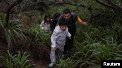一家来自中国的移民渡过美墨边境的格兰德河正在走出美国德克萨斯州的丛林。（2023年4月4日）