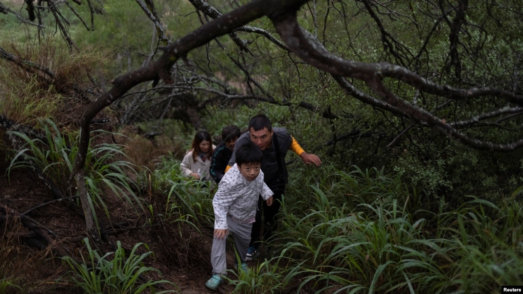 资料照：一家来自中国的移民渡过美墨边境的格兰德河正在走出美国德克萨斯州的丛林。（2023年4月4日）
